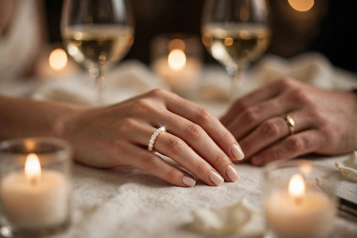 Couple's hands resting on a candlelit anniversary dinner table with champagne glasses, the woman wearing a MARWAH lab-grown diamond eternity band
