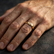 Bezel-set solitaire diamond band in yellow gold, worn on a man's ring finger — MARWAH