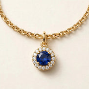 Birthstone Diamond Charm, blue sapphire with a diamond halo on a fine chain bracelet in yellow gold, charm detail view.