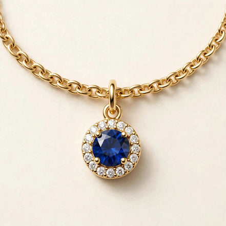 Birthstone Diamond Charm, blue sapphire with a diamond halo on a fine chain bracelet in yellow gold, charm detail view.