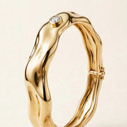 Sculptural Gold Bangle with Diamond Accent, single bezel-set round diamond on a molten-form bangle in yellow gold, three-quarter detail view.