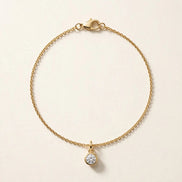 Solitaire Diamond Charm, round brilliant diamond in a slim bezel on a fine chain bracelet in yellow gold, full view.