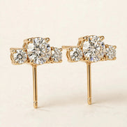 Three-Stone Diamond Studs, three graduated round diamonds in yellow gold, three-quarter detail view.