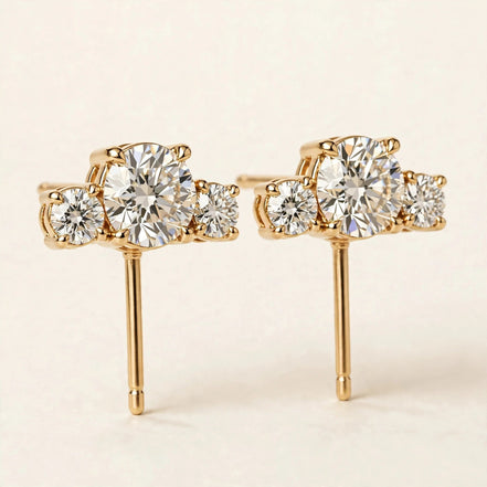 Three-Stone Diamond Studs, three graduated round diamonds in yellow gold, three-quarter detail view.