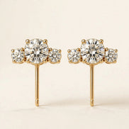 Three-Stone Diamond Studs, three graduated round diamonds in yellow gold, pair front view.