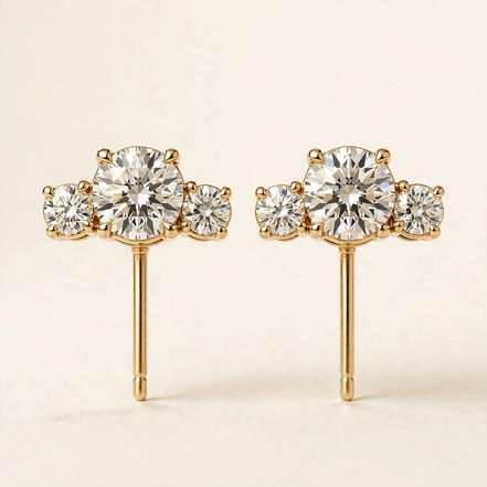 Three-Stone Diamond Studs, three graduated round diamonds in yellow gold, pair front view.