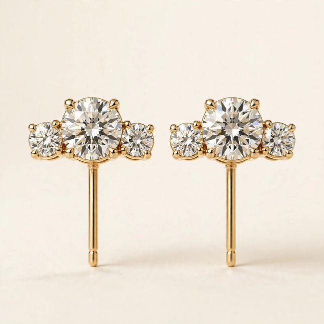 Three-Stone Diamond Studs, three graduated round diamonds in yellow gold, pair front view.