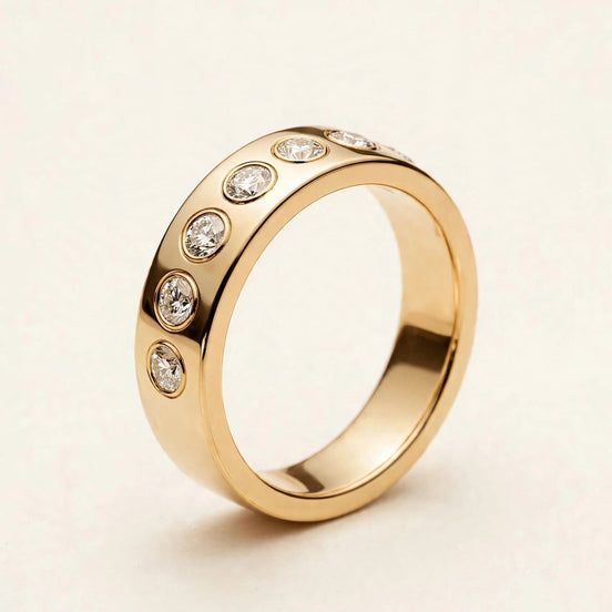 Wide Cigar Diamond Band, seven bezel-set round diamonds in a single row on a flat polished band in yellow gold, front view.