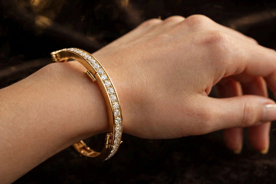Hinged diamond bangle in yellow gold worn on a woman's wrist, alternate view — MARWAH